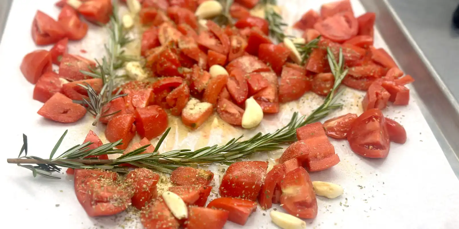 tomatoes, rosemary and garlic on a roasting sheet
